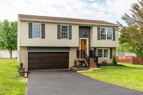 Split-level home exterior with dark accent siding and a chandelier over the entry