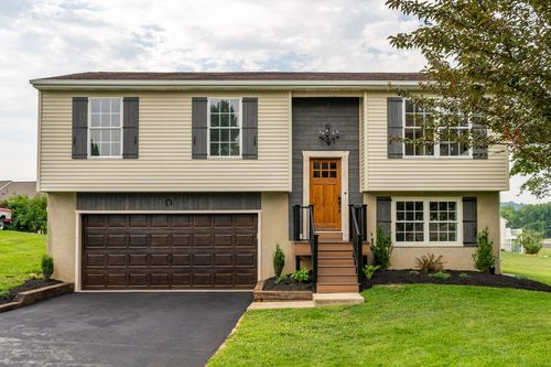 Split-level home front entry with black shutters and a hanging chandelier