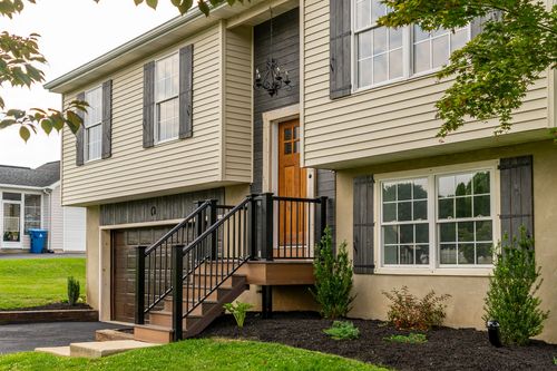 Front entry with a wood door, black railings and a hanging chandelier
