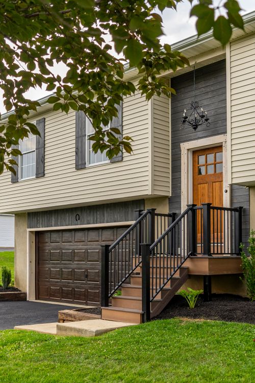 Close view of the front entry steps, wood door and black metal railing
