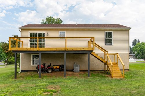 Elevated rear deck with a wood railing and stairs leading down to the yard