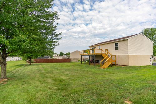 Rear exterior with an elevated deck and open yard bordered by a wood fence