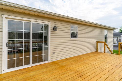 Wood deck along the rear of the home with a window and sliding door
