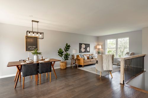 Open dining and living area with a wood table, dark chairs and a layered area rug
