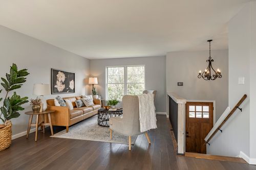 Living room with a tan sofa, chandelier and staircase landing