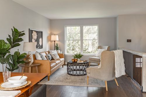 Living room with a tan leather sofa, round metal coffee table and accent chairs