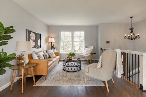 Living room seating area with a chandelier over the adjacent staircase