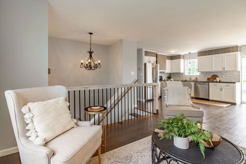 Open-concept living area with a chandelier over the stairwell and kitchen beyond