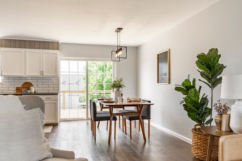 Dining area with a wood table, gray upholstered chairs and pendant lighting