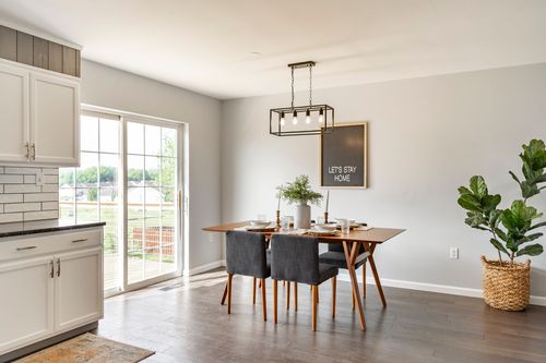Dining area with a wood table and a Let's Stay Home sign on the wall