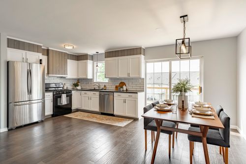 Open kitchen and dining area with white cabinets and a stainless refrigerator