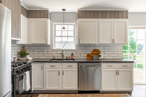 Kitchen with white cabinets, black granite counters and a gas range