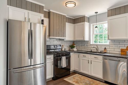 Kitchen with a stainless refrigerator, subway tile and black granite counters