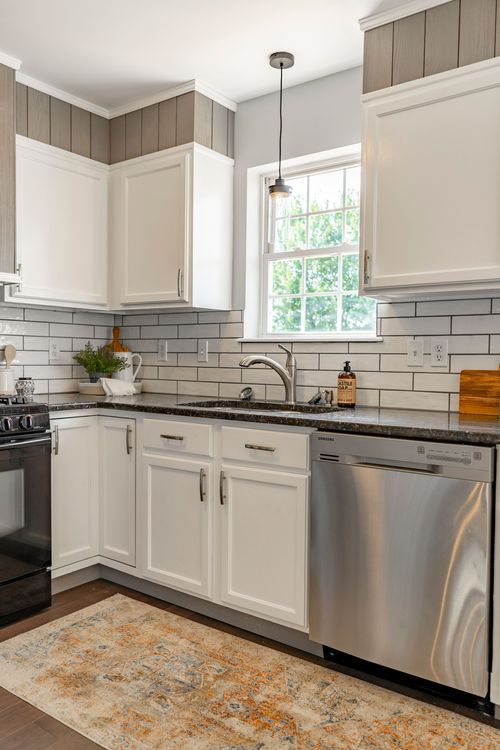 Kitchen with white cabinetry, black granite counters and pendant lighting