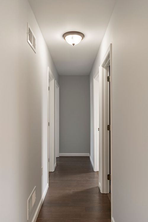 Hallway with white doors and rich wood flooring