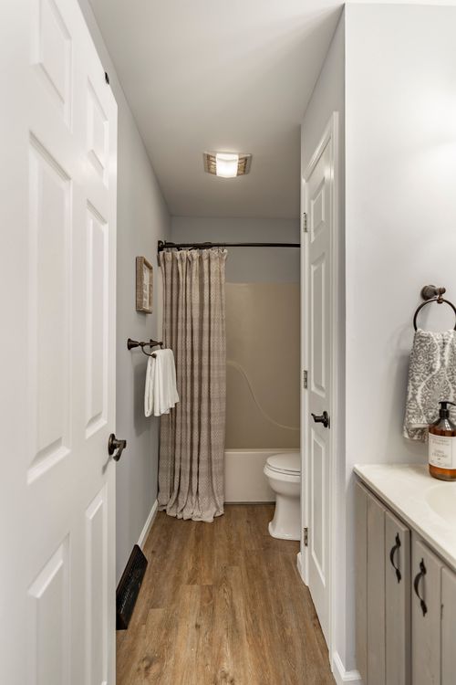 Bathroom with a patterned shower curtain, tub and wood-look vinyl flooring