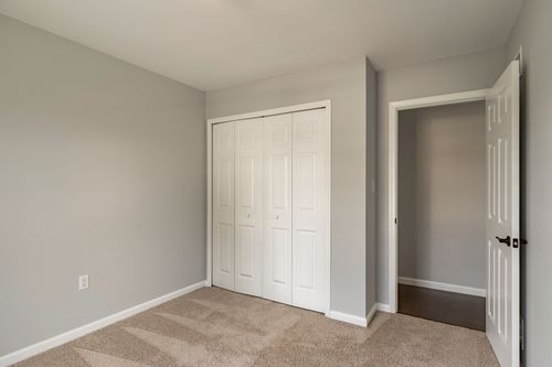 Empty bedroom with white bifold closet doors and a doorway to the hall