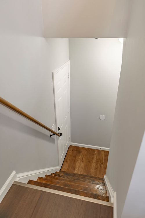 Staircase leading down to a wood floor landing and white door