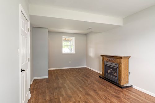 Lower-level room with wood flooring and a freestanding gas fireplace