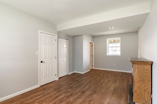 Lower-level bedroom with wood flooring, closet doors and a dresser