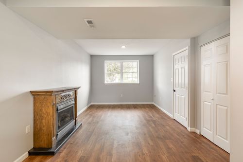 Lower-level family room with wood flooring and a wood-mantel fireplace
