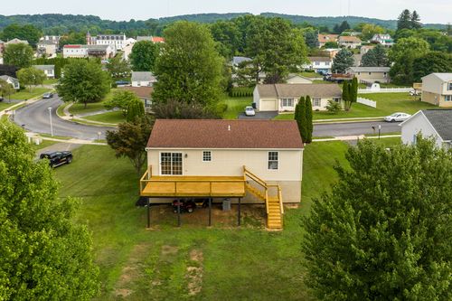 Aerial view of a raised ranch home with an elevated deck and carport below