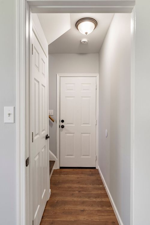 Entry hallway with wood flooring leading to the front door