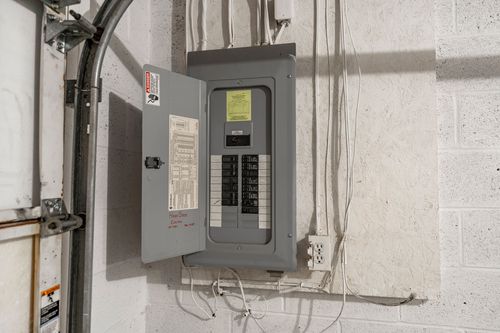 Close view of an open electrical panel mounted on a concrete block wall
