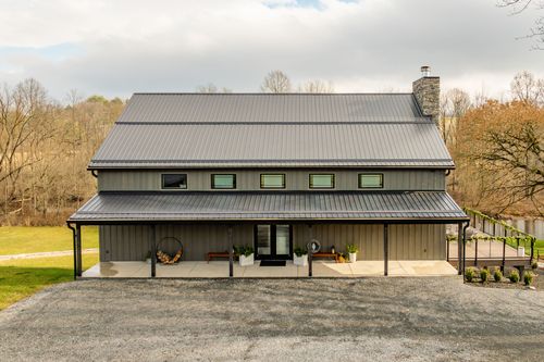 Front exterior view of a barn venue decorated with holiday garland over the entry