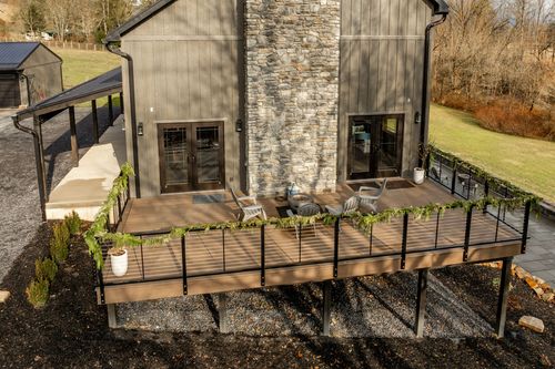 Aerial view of an elevated deck with a stone chimney and garland-wrapped railing