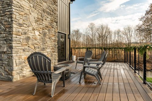 Deck corner with a stone chimney, Adirondack chairs and a fire pit