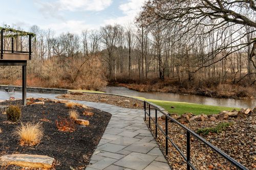 Stone walkway winding along a creek lined with bare trees