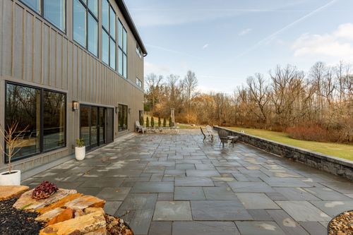 Stone patio with outdoor seating beneath tall glass windows