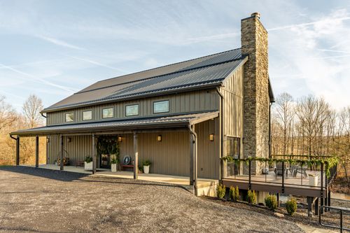 Barn-style venue corner view with a stone chimney and elevated back deck