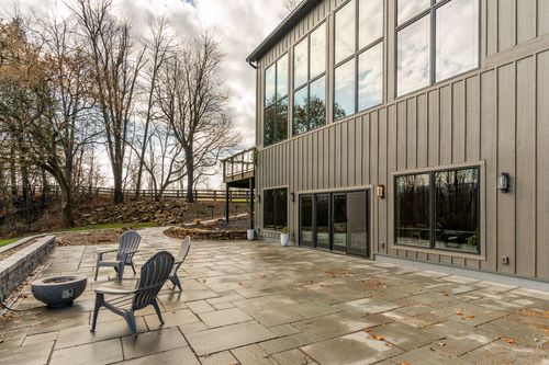 Stone patio with black Adirondack chairs beside the venue's tall glass windows