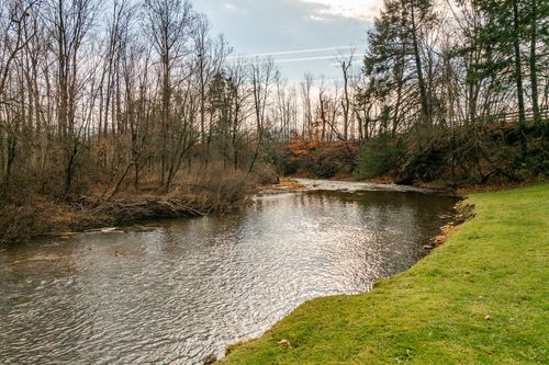 Wooded creek winding through bare trees with rust-colored autumn foliage