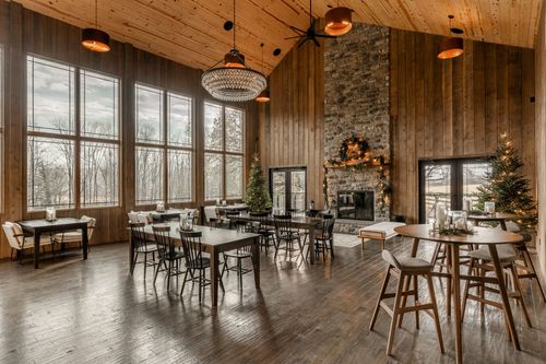 Vaulted wood-paneled event room with a stone fireplace, crystal chandelier and long dining tables
