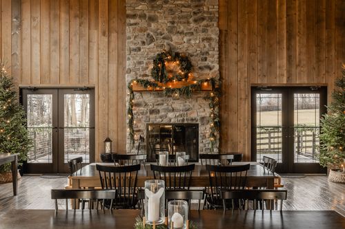 Reception hall with wood plank walls, pendant lighting and long tables set for dinner