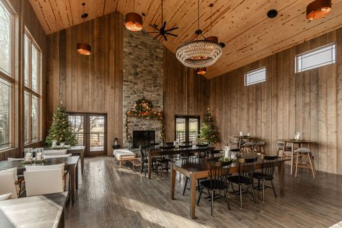 Cozy sitting area with a stone fireplace, garland and a wood bench beneath tall windows