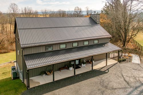 Aerial close-up of a barn-style venue with a wraparound covered porch