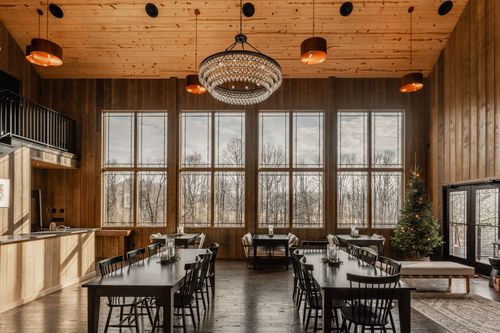 Two-story event space with a black iron staircase, chandelier and long dining tables