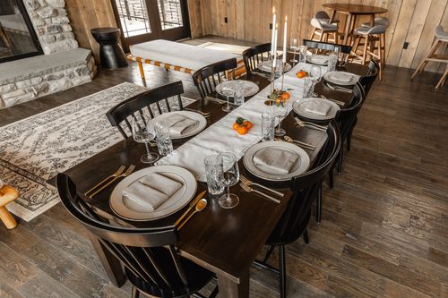 Long dining table set with white gold-rimmed china, gold flatware and citrus centerpieces