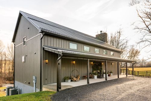 Corner exterior view of a board-and-batten venue building with a covered porch