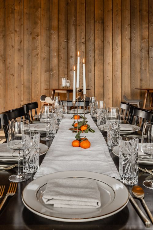 Elegant table setting with tall taper candles, crystal glassware and fresh clementines