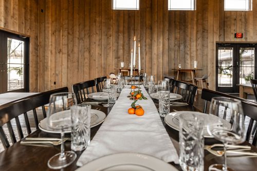 Formal table setting beneath tall windows with lit taper candles and a citrus centerpiece