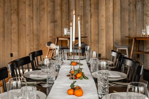 Table set with gold candlesticks, crystal stemware and a citrus and greenery centerpiece
