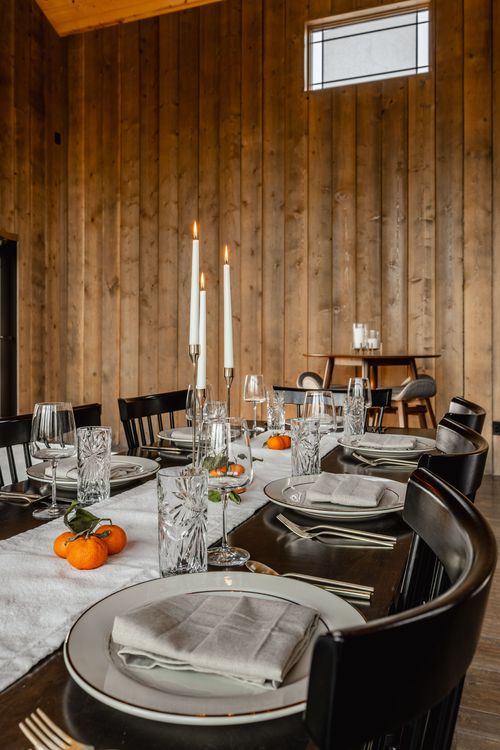Curved dining table set with lit taper candles, gold flatware and neutral linen napkins