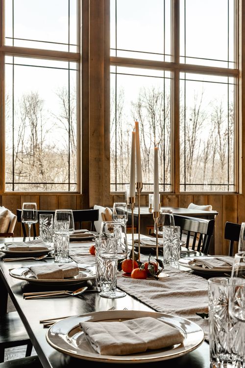 Table setting near floor-to-ceiling windows with a wooded view, crystal glasses and citrus accents