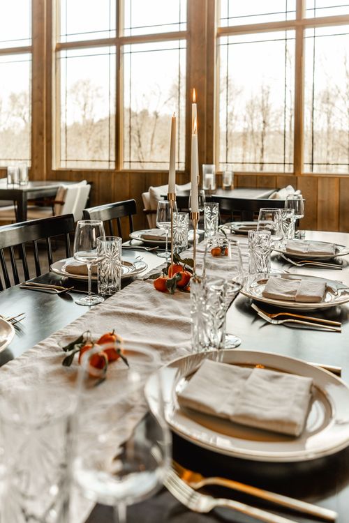 Long table set beneath a stone fireplace with a framed landscape painting on the mantel