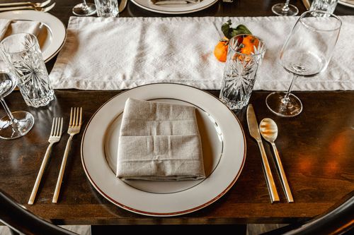 Table set with three lit taper candles beside a stone fireplace and hearth